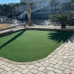 A manicured putting green next to a paved walkway